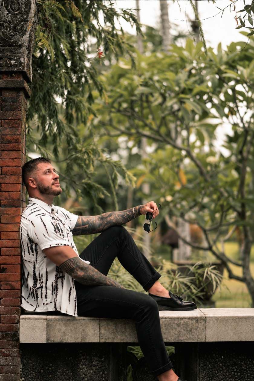 Connor sitting on a garden wall, looking up into the trees