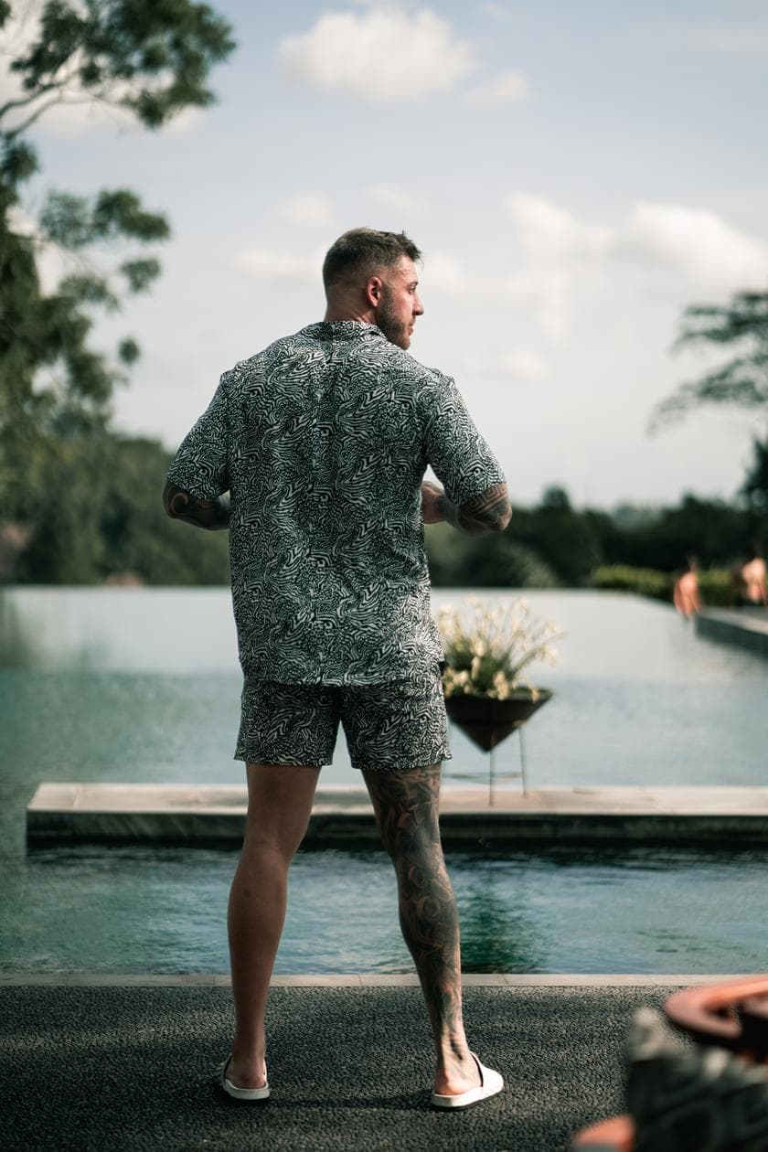 Connor standing at the edge of an infinity pool, looking out over the jungle
