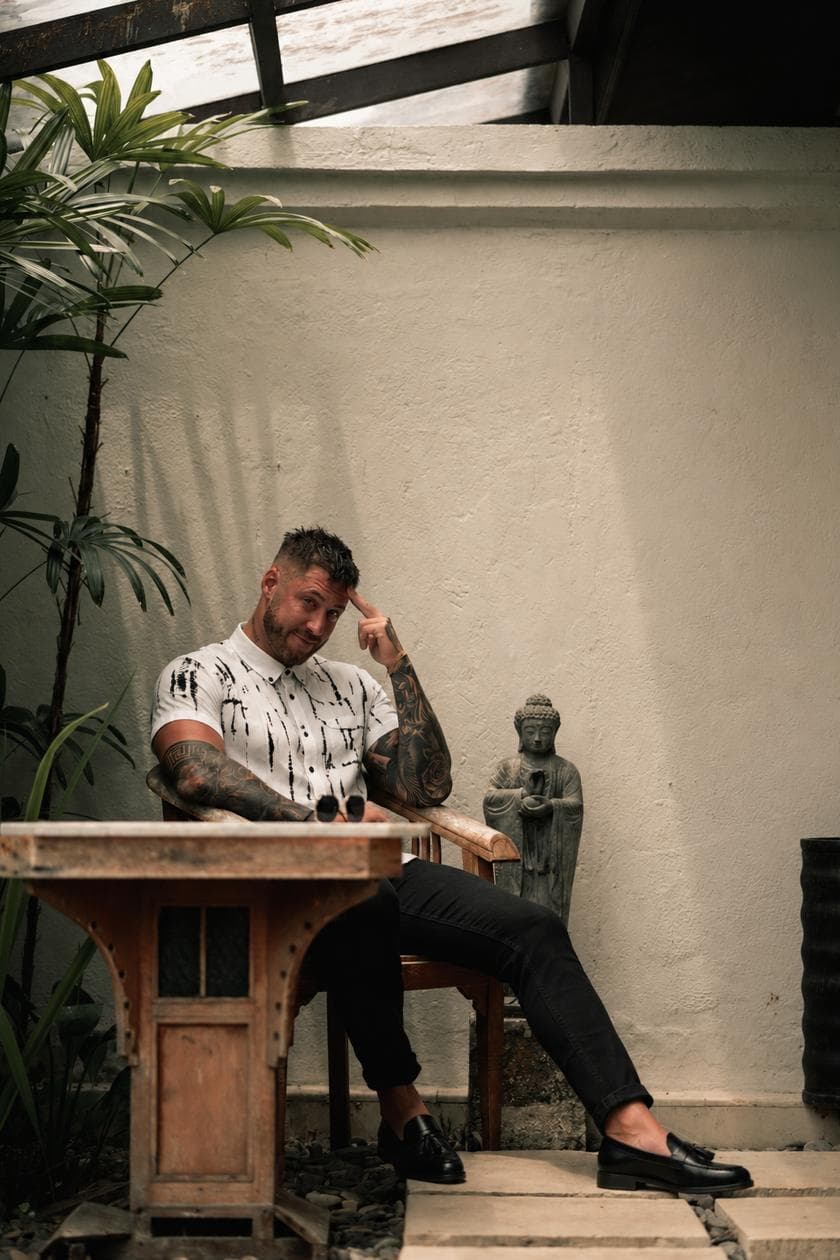 Connor at a wooden table on a patio, finger to his temple, mid-thought