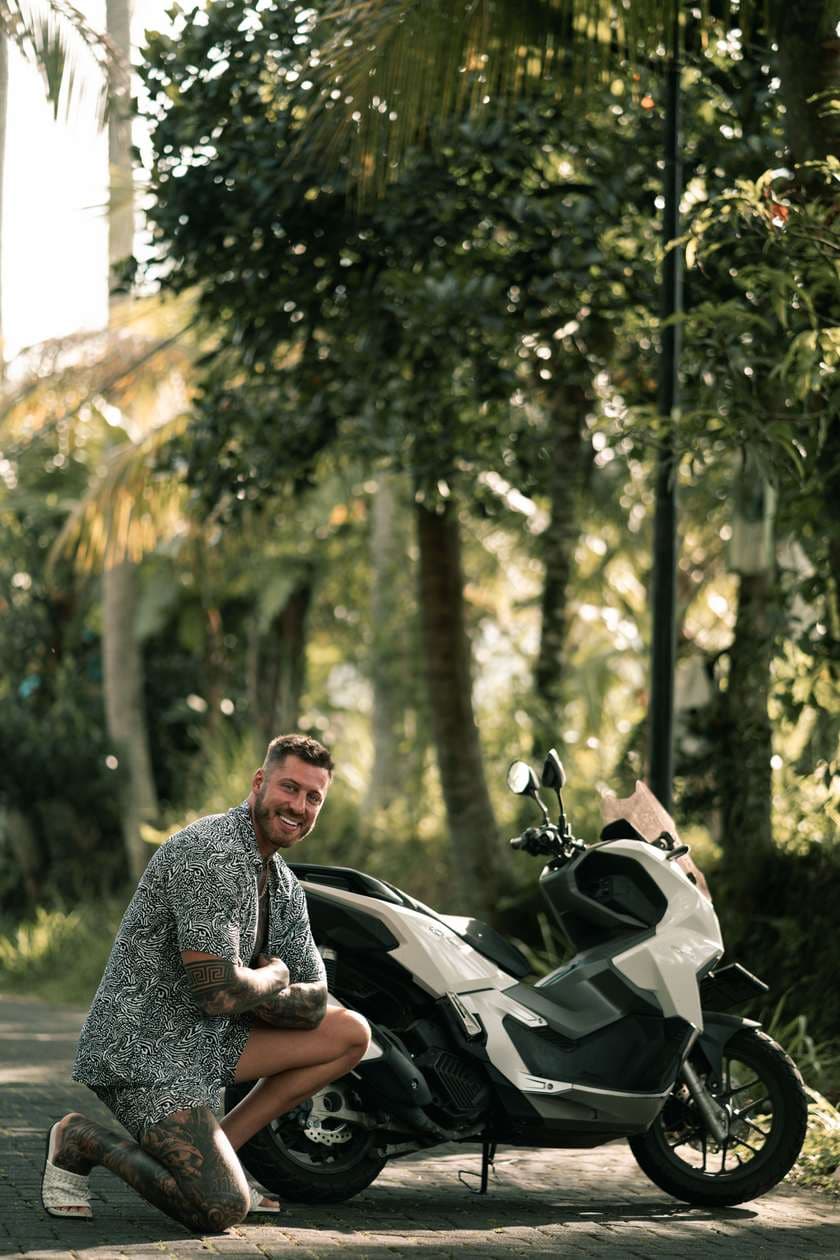 Connor kneeling beside his scooter on a jungle road