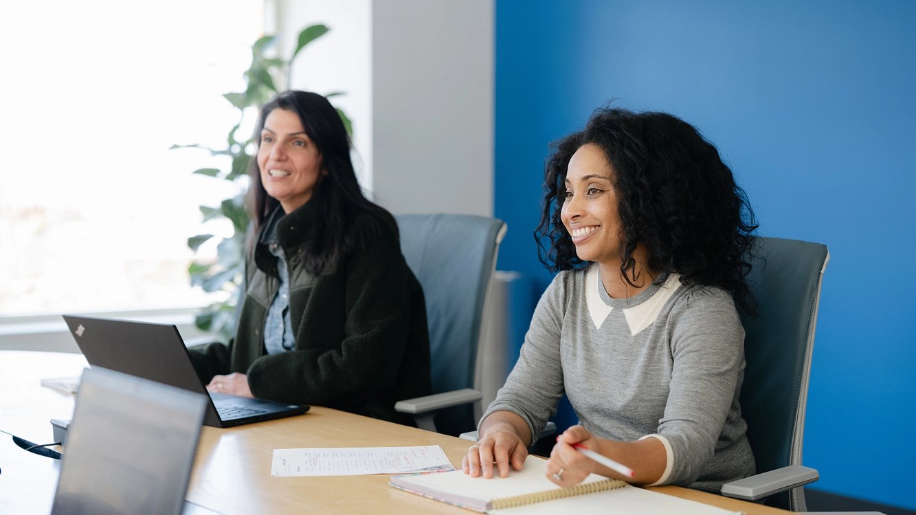 Two 4DMT colleagues smiling during an office meeting