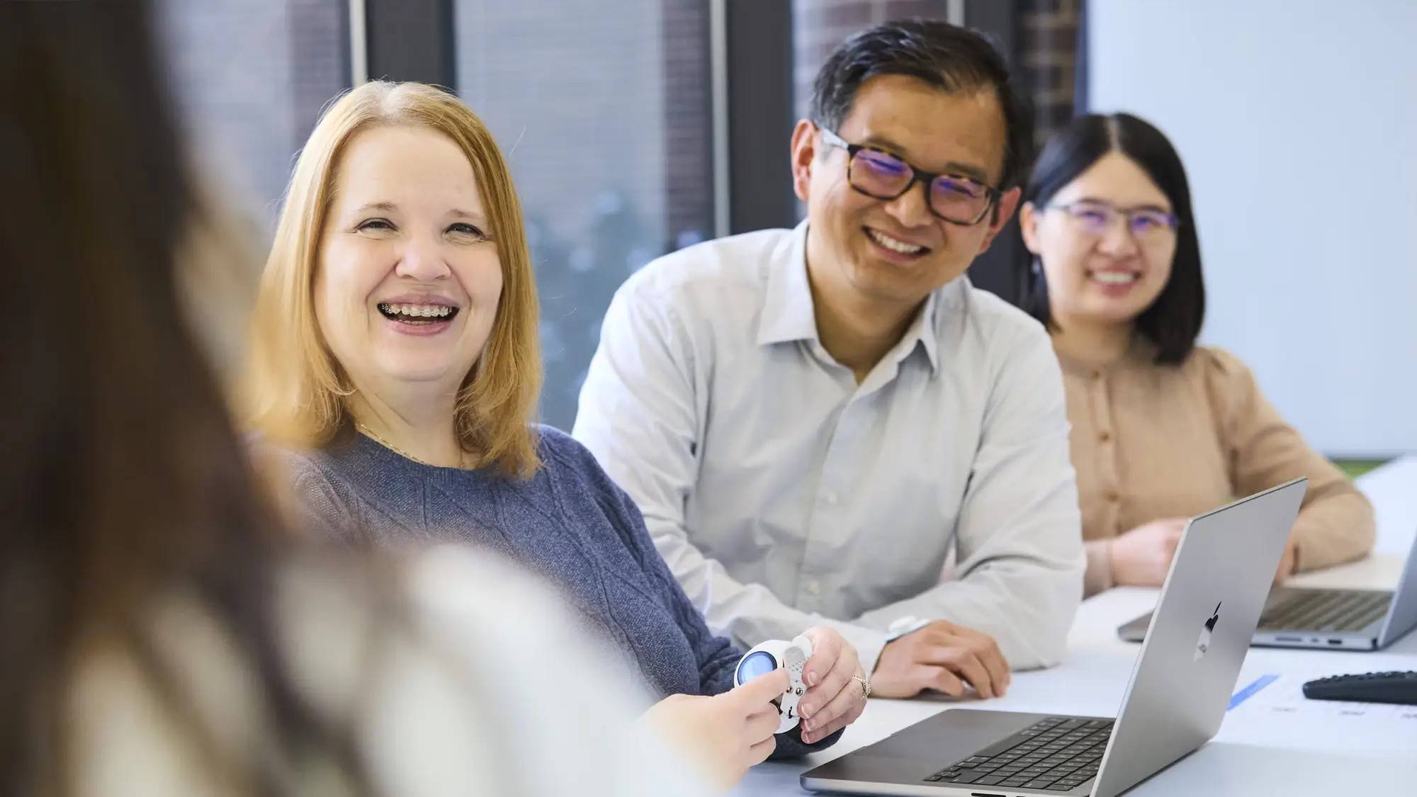 Three AbbVie colleagues laughing together at a meeting table