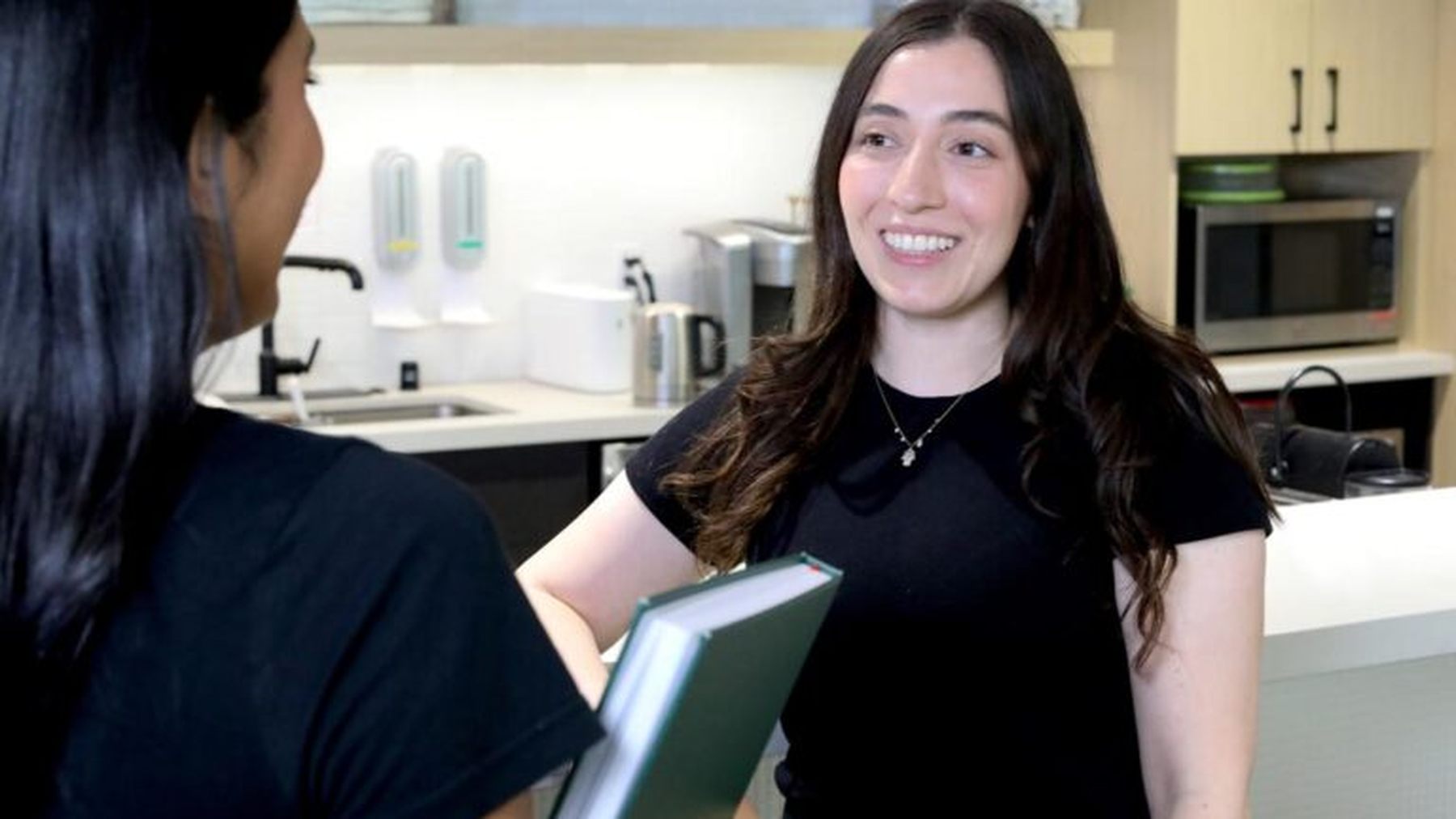 ADARx colleagues smiling during a conversation in an office kitchen