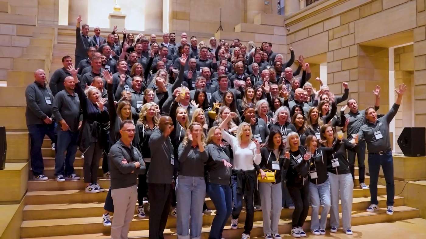 More than a hundred Amneal colleagues cheering and waving on a stone staircase at a company gathering