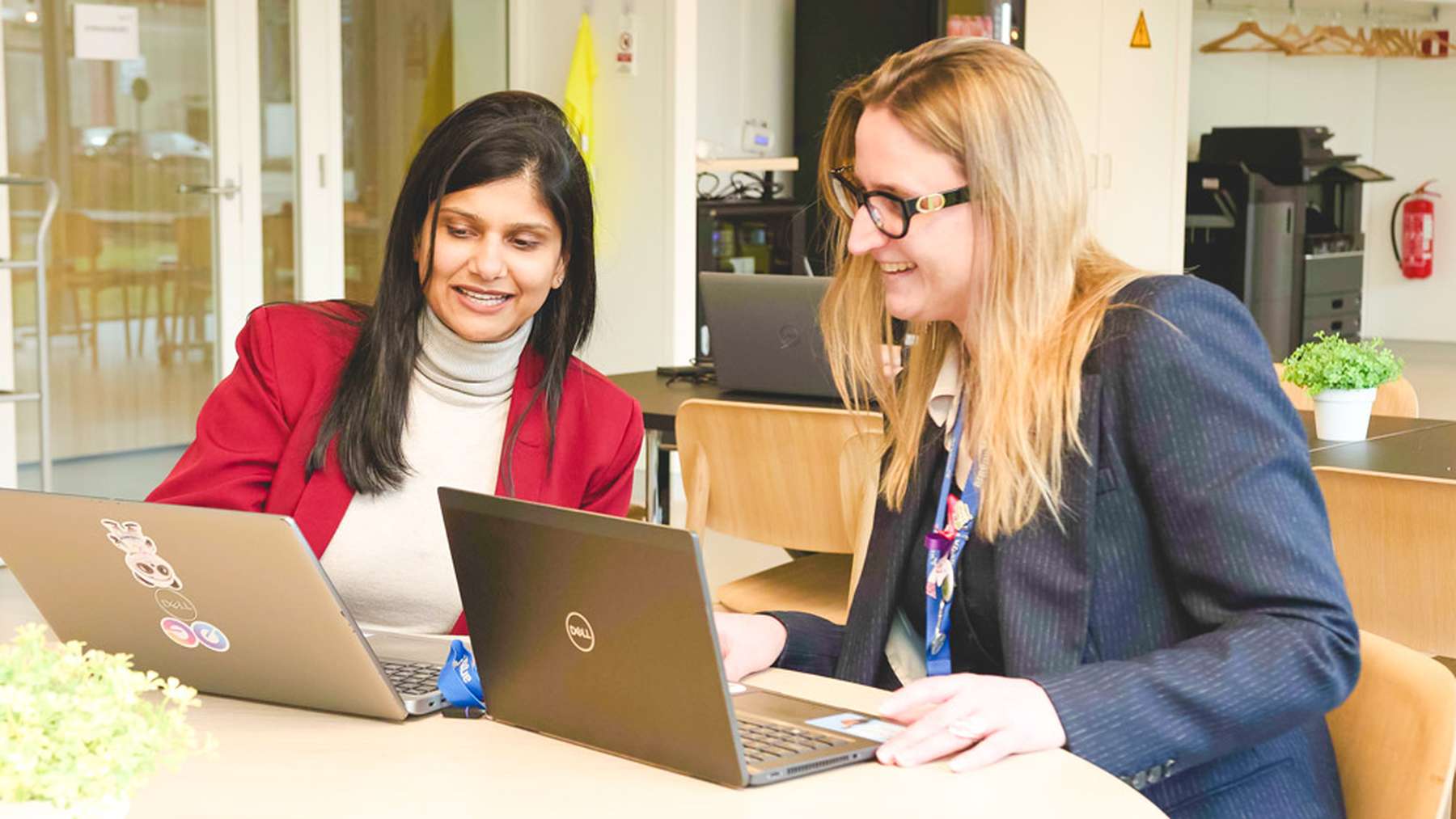 Two smiling argenx colleagues working together at their laptops