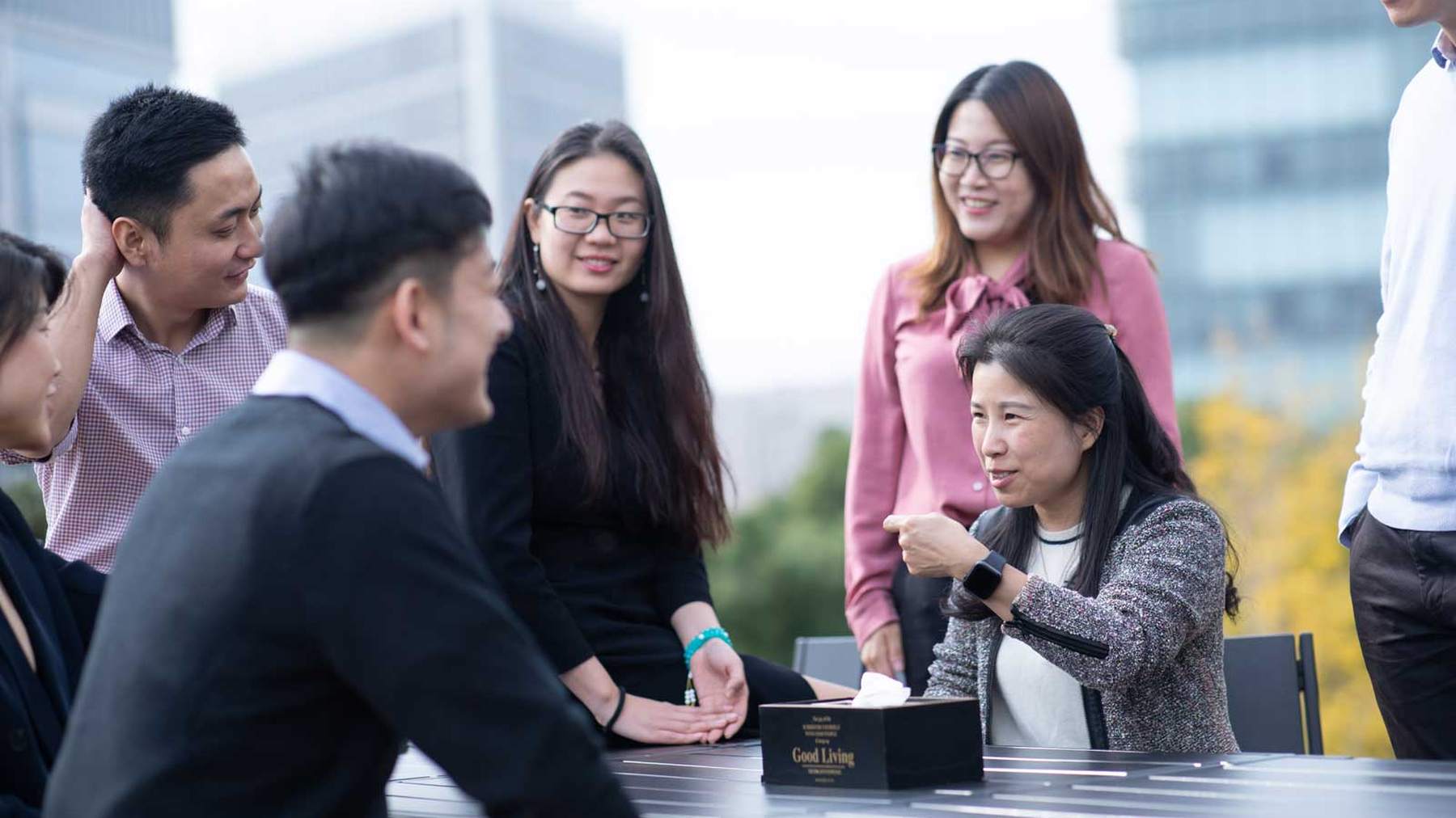 A group of smiling AstraZeneca colleagues in China chatting around an outdoor table