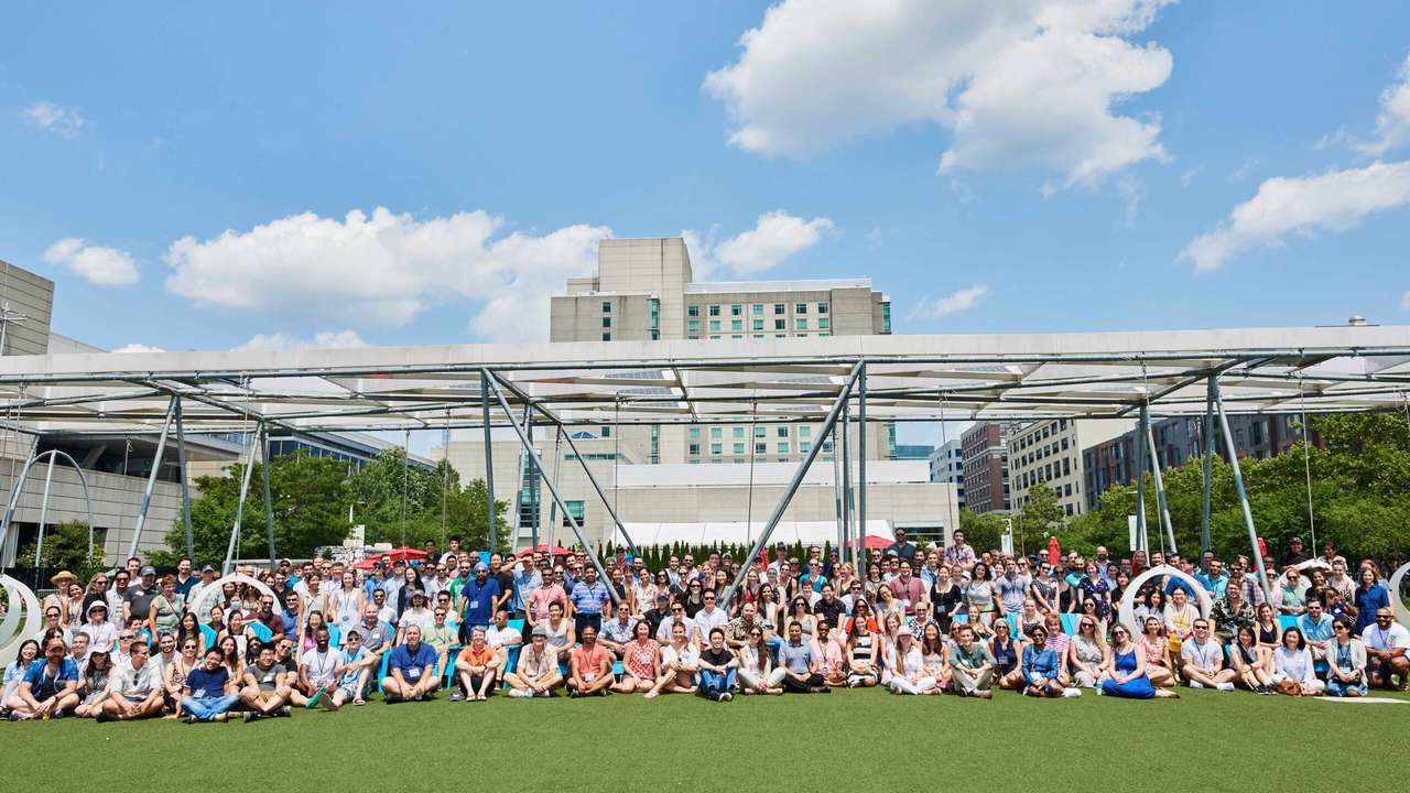 Hundreds of Beam colleagues sitting together on a lawn for an all-company photo on a sunny day