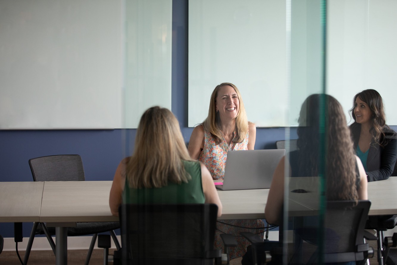 Bicara colleagues discussing their work around a meeting table