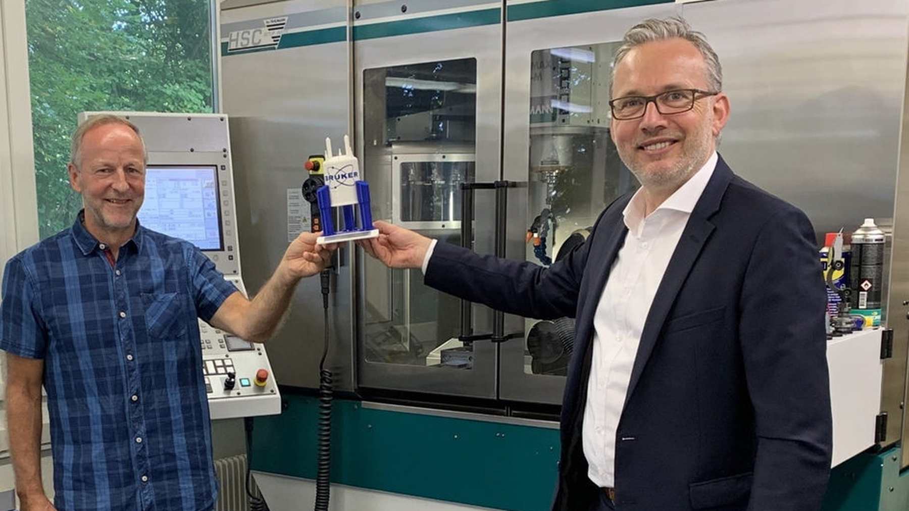A Bruker representative recognizing a supplier beside manufacturing equipment