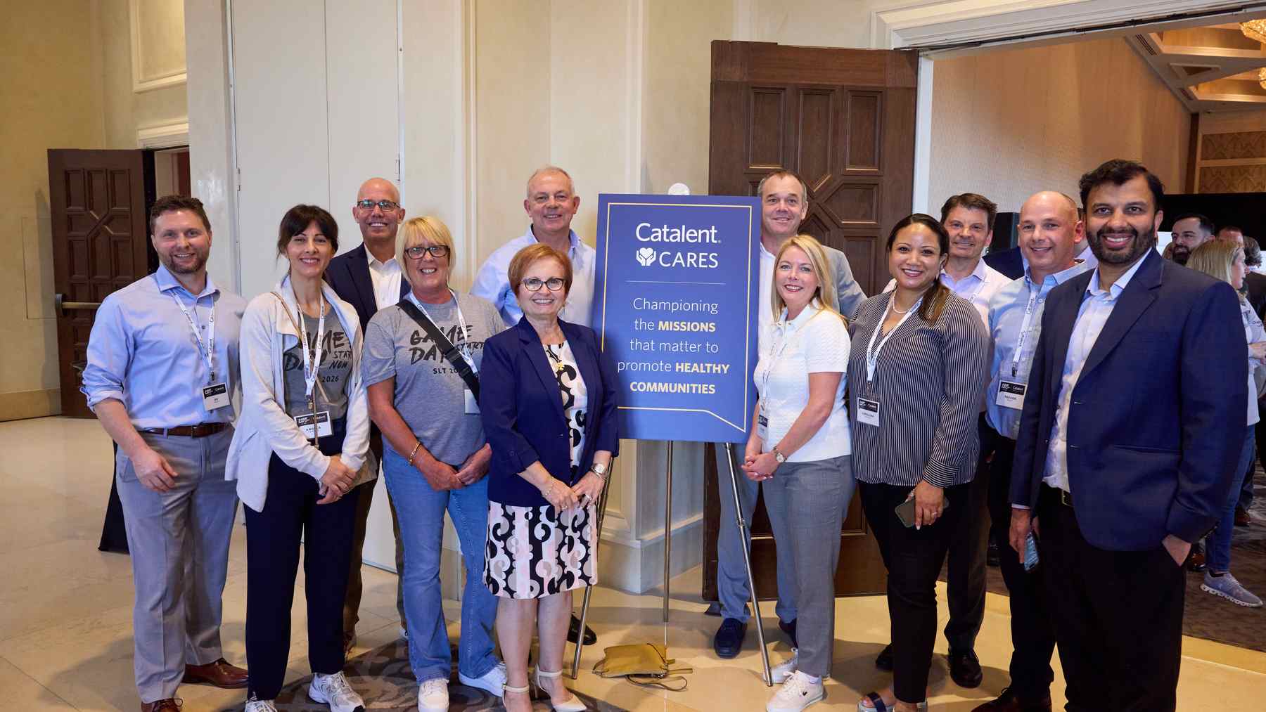 About eighteen smiling Catalent colleagues gathered around a Catalent Cares sign at a company event