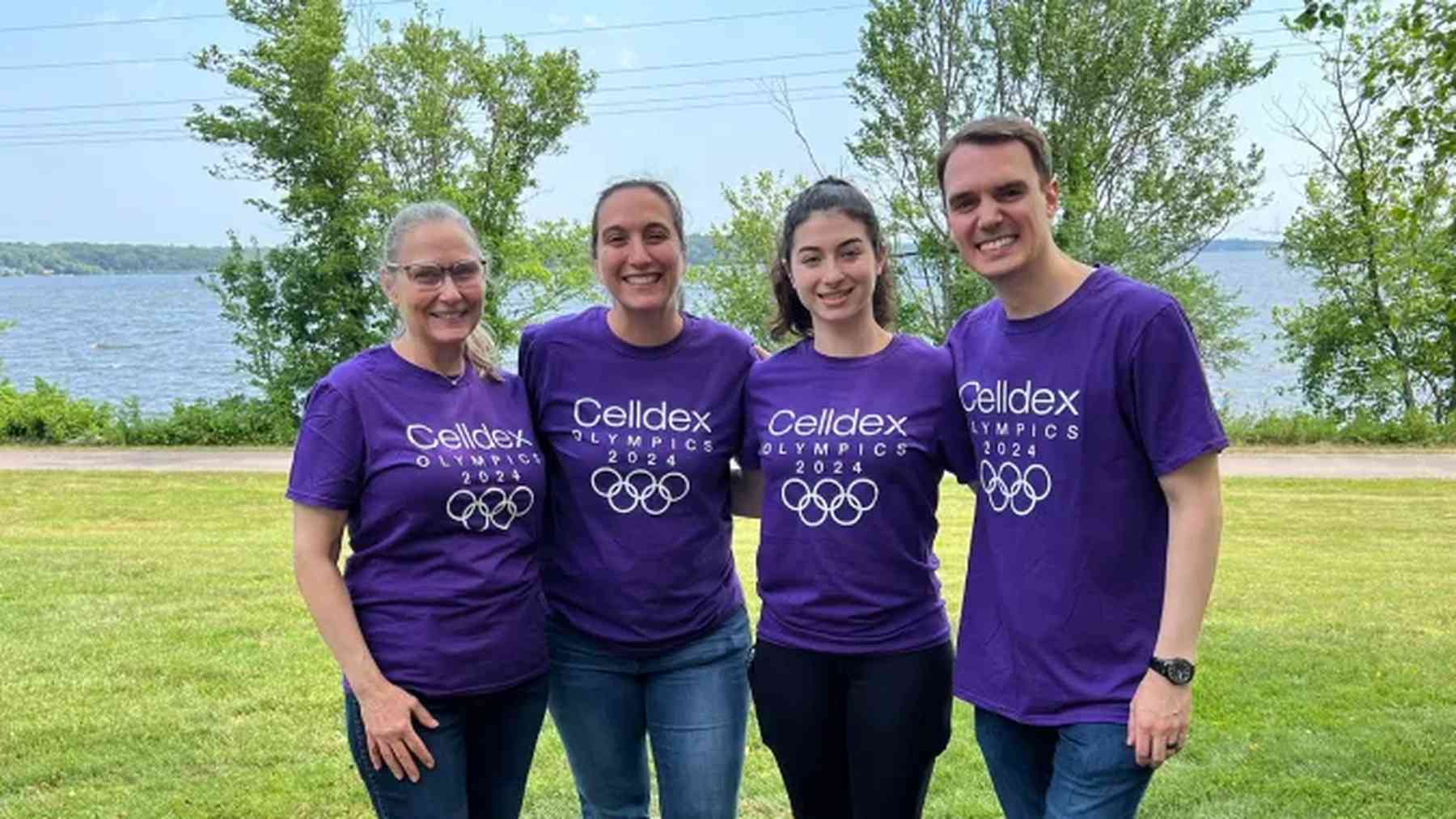 Four Celldex colleagues in matching shirts standing together beside a lake