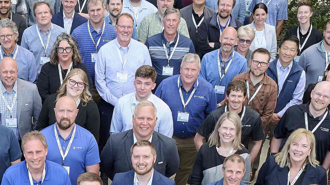 Dozens of smiling Cretex colleagues with name badges gathered close together for a team photo