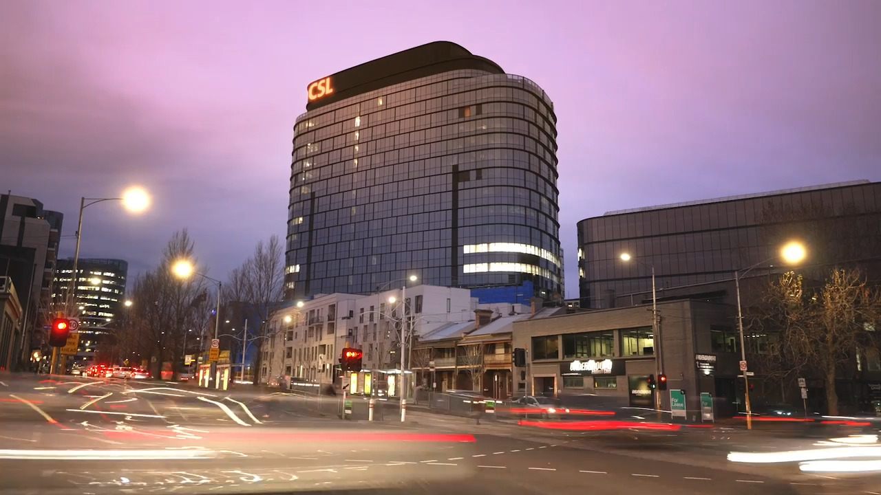 CSL's Melbourne headquarters tower lit up at dusk above a busy city street