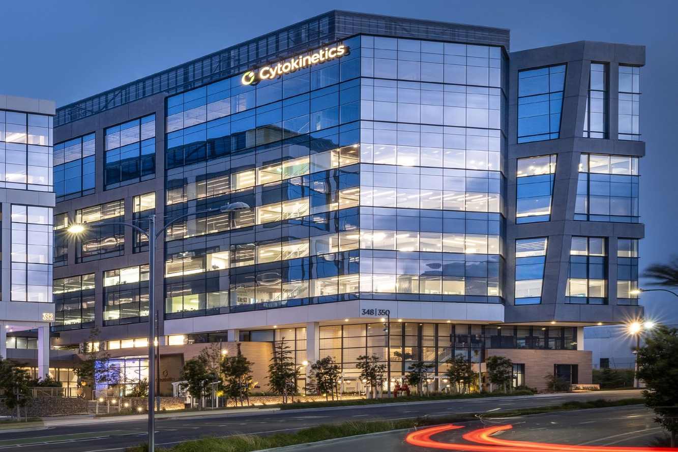 The glass Cytokinetics headquarters building in South San Francisco lit up at dusk
