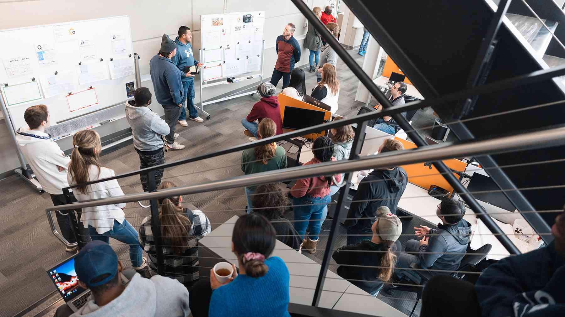 A large group of Aldevron associates gathered around whiteboards for a team huddle