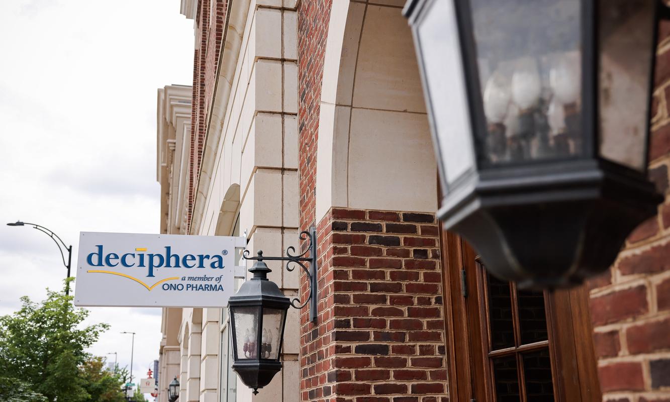 The Deciphera, a member of Ono Pharma sign hanging beside lanterns on a brick office building