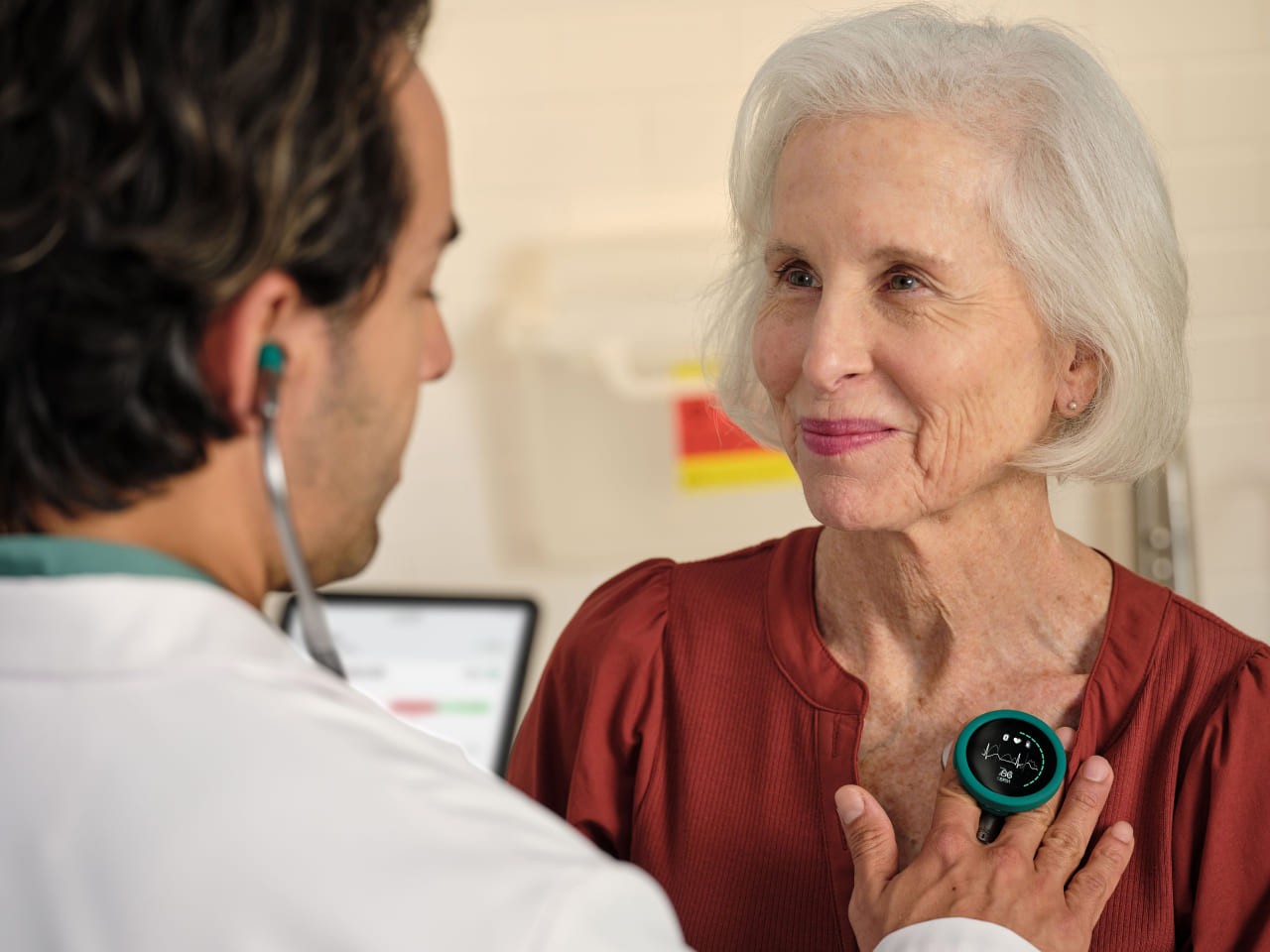 A clinician listening to a smiling patient's heart with an Eko CORE 500 digital stethoscope