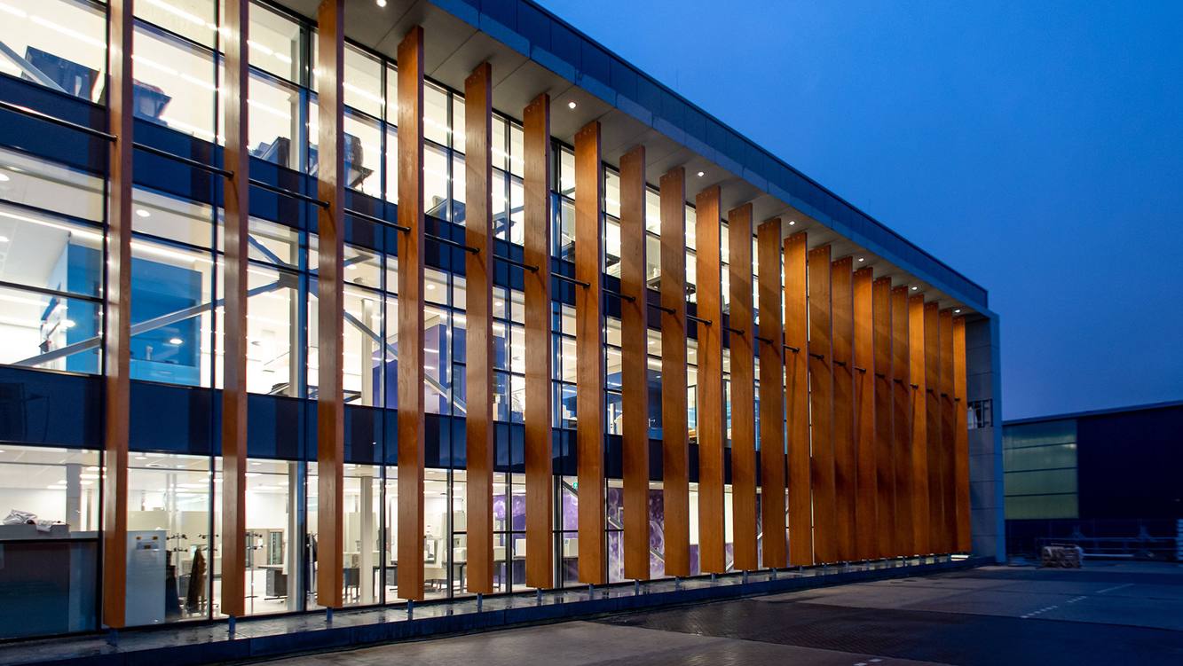 Gilead's cell therapy manufacturing facility in the Netherlands, its glass and wood facade lit at dusk