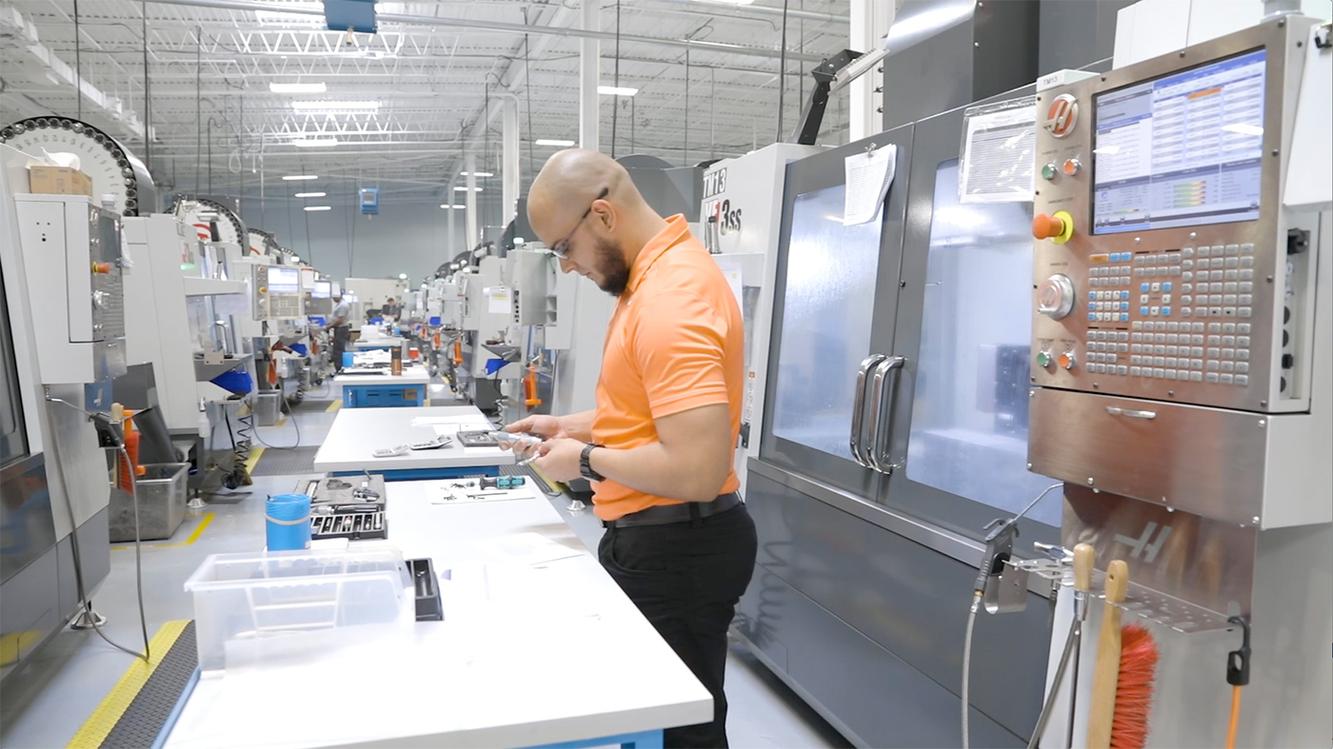 Globus Medical employee inspecting a component beside machining equipment