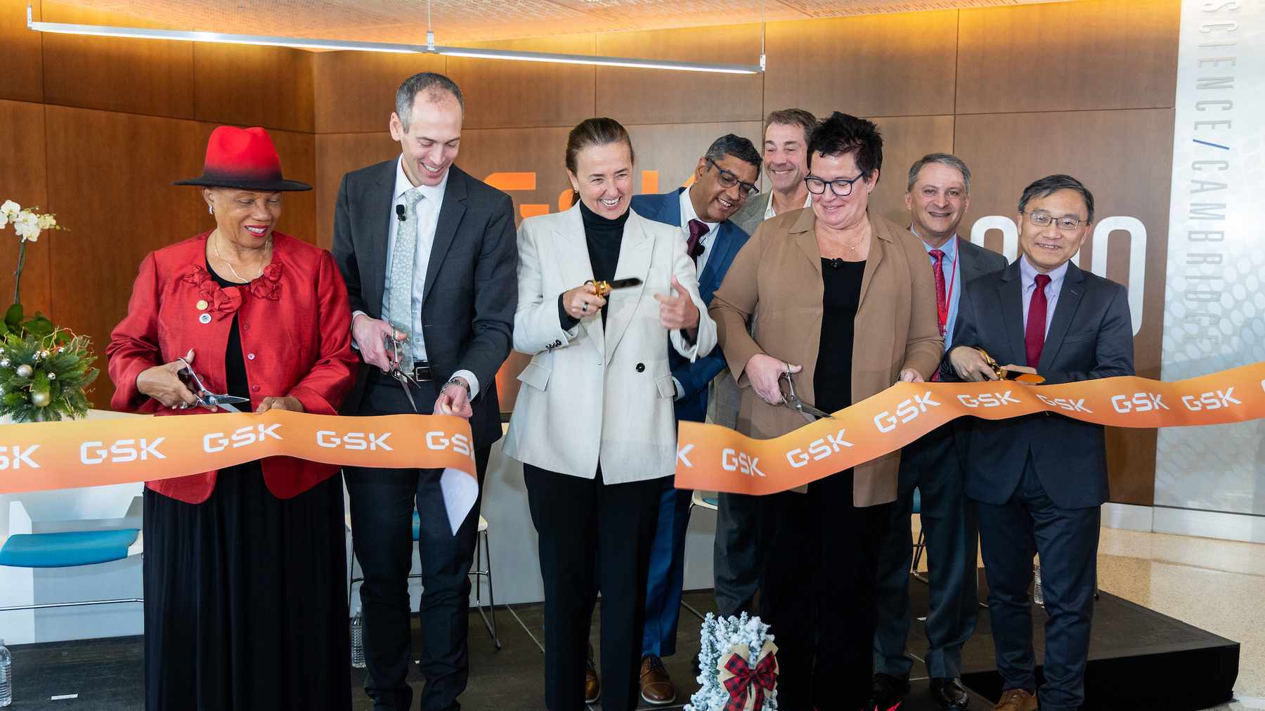 Smiling GSK leaders and colleagues cutting an orange GSK ribbon to open new labs in Cambridge