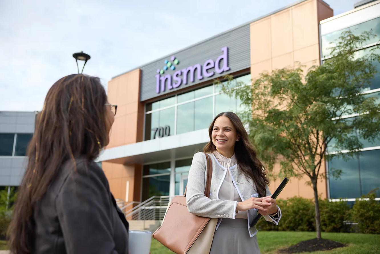 A smiling Insmed colleague outside the Insmed headquarters building in Bridgewater, New Jersey