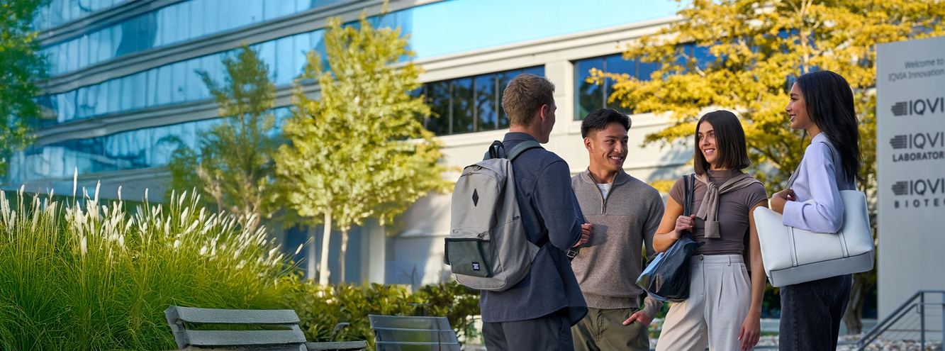 IQVIA colleagues talking outside a glass office building with IQVIA Laboratories signage