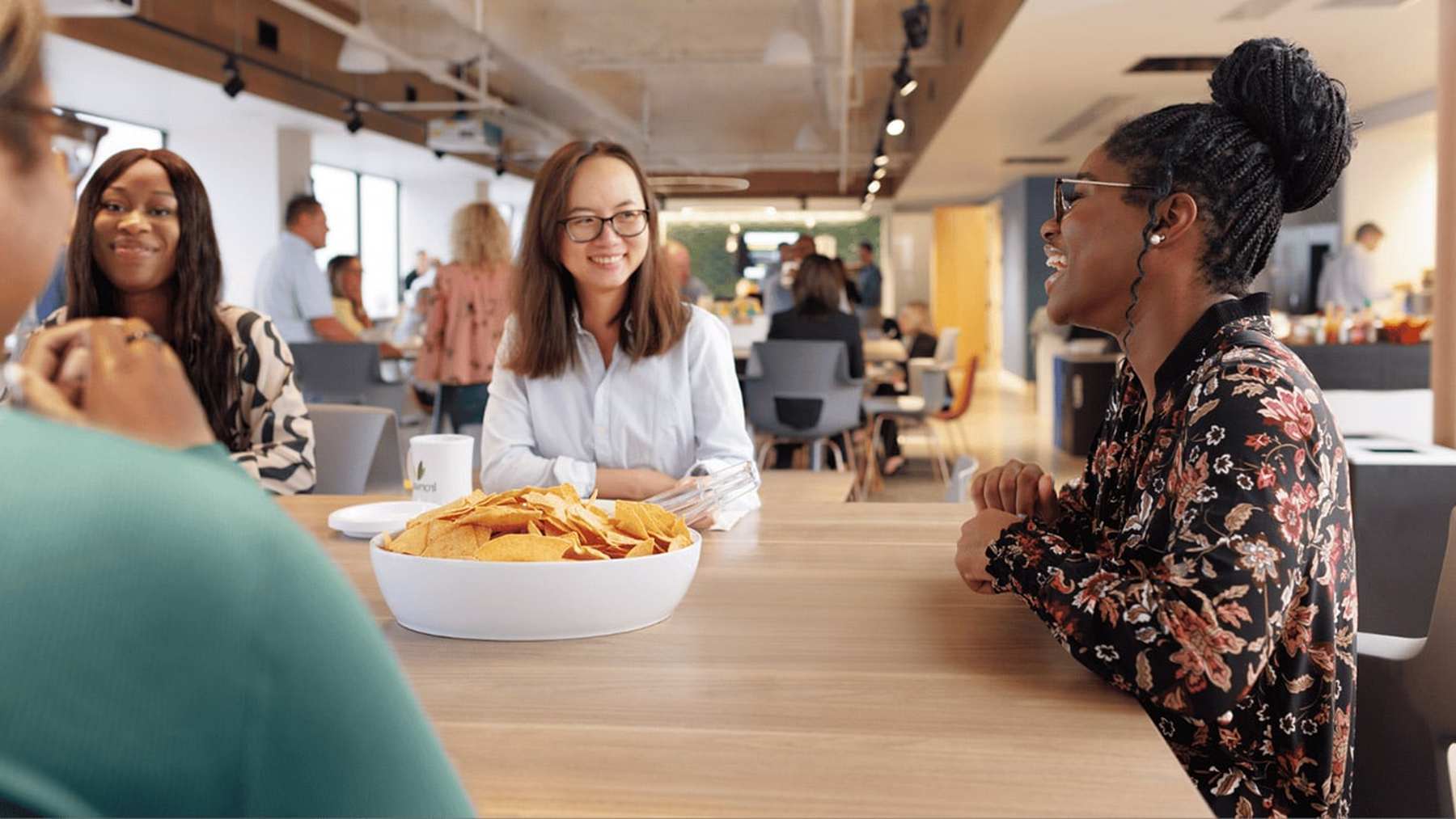 Ironwood colleagues smiling and talking over lunch at a long office table