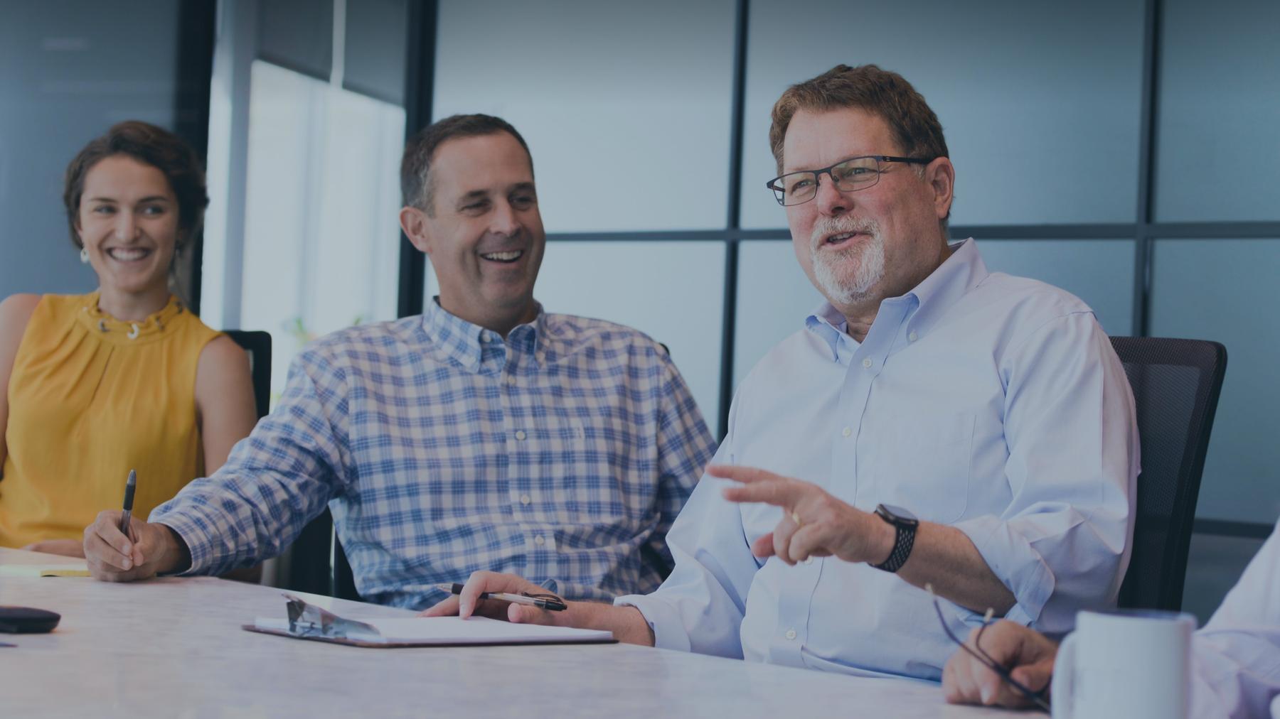 Three Janux colleagues laughing together at a conference table