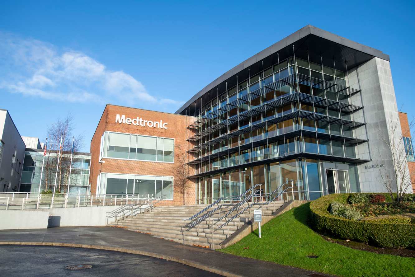 Medtronic's glass and brick headquarters building in Galway, Ireland, under a blue sky