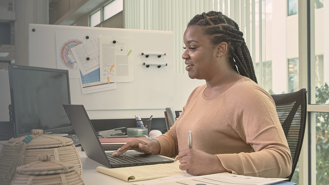 A Parexel colleague smiling as she works at her laptop in a bright office