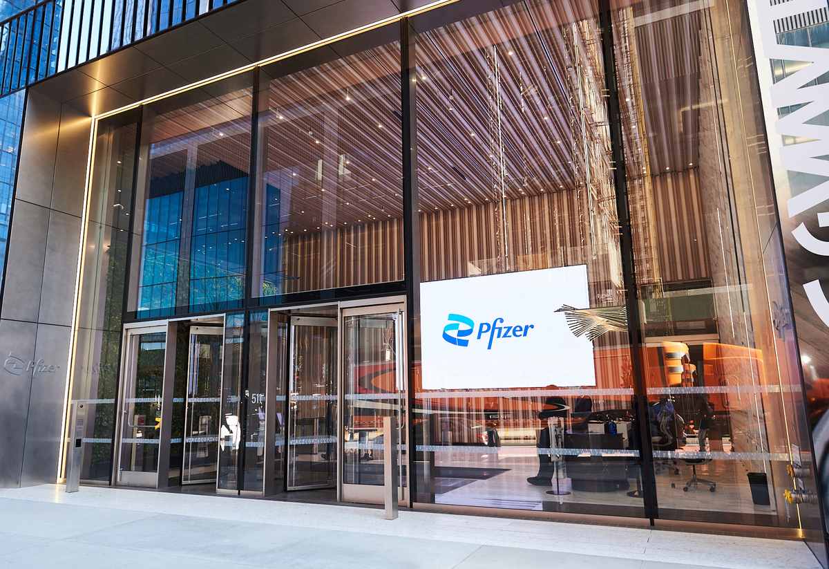 The glass entrance of Pfizer's New York headquarters with the Pfizer logo on a lobby screen
