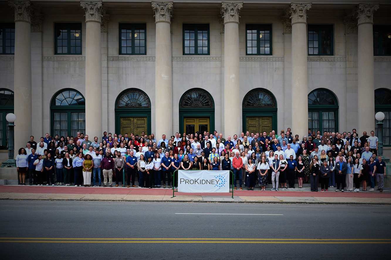 Hundreds of ProKidney employees gathered on the steps of a columned building behind a ProKidney banner