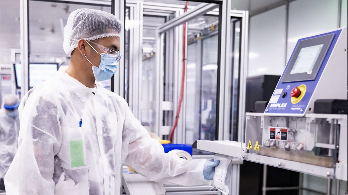 A QuidelOrtho manufacturing operator working with diagnostic product packaging equipment