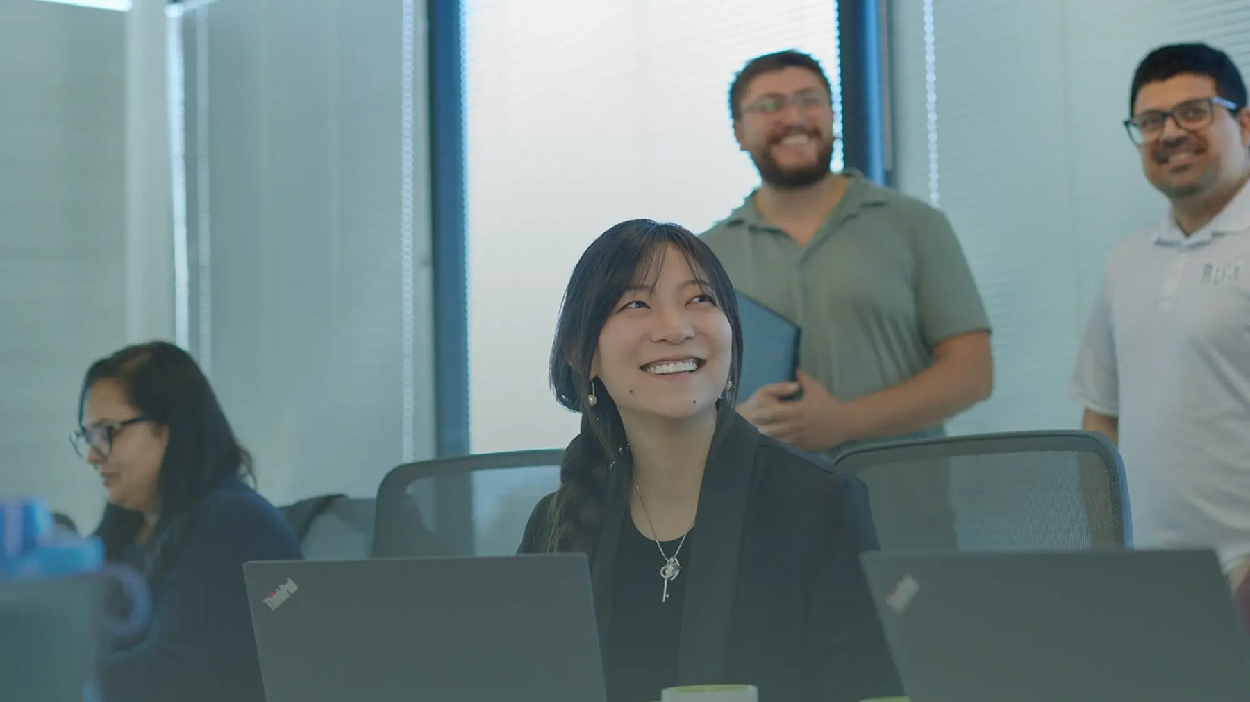 Revolution Medicines colleagues smiling together around a conference table with laptops