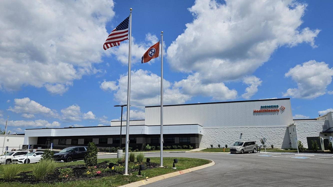 A Siemens Healthineers building with US and Tennessee flags in front under a blue sky with clouds