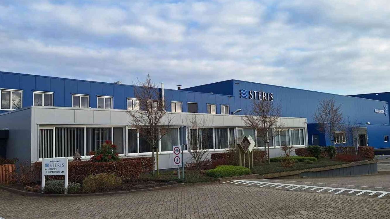 STERIS's laboratory in Ede, the Netherlands, a long blue and white building with the STERIS name under a cloudy sky