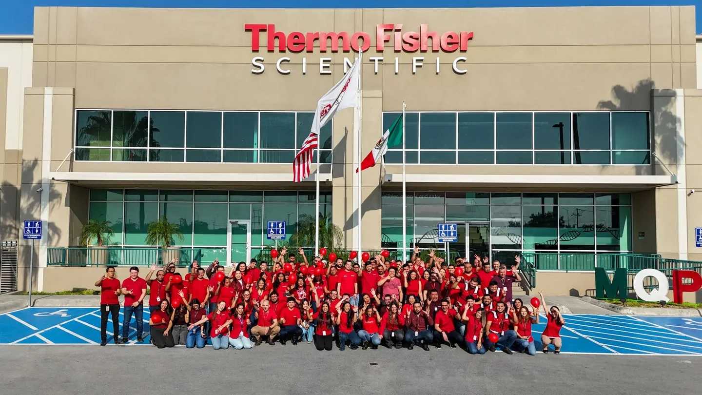 About a hundred Thermo Fisher colleagues in red shirts gathered in front of their Thermo Fisher Scientific plant