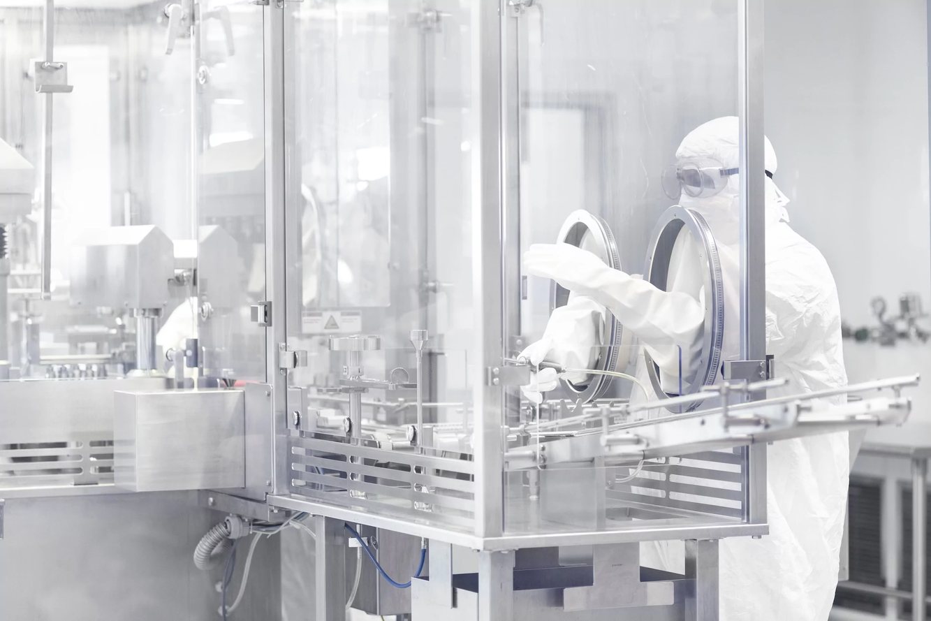 A Tolmar employee operating aseptic manufacturing equipment in a cleanroom