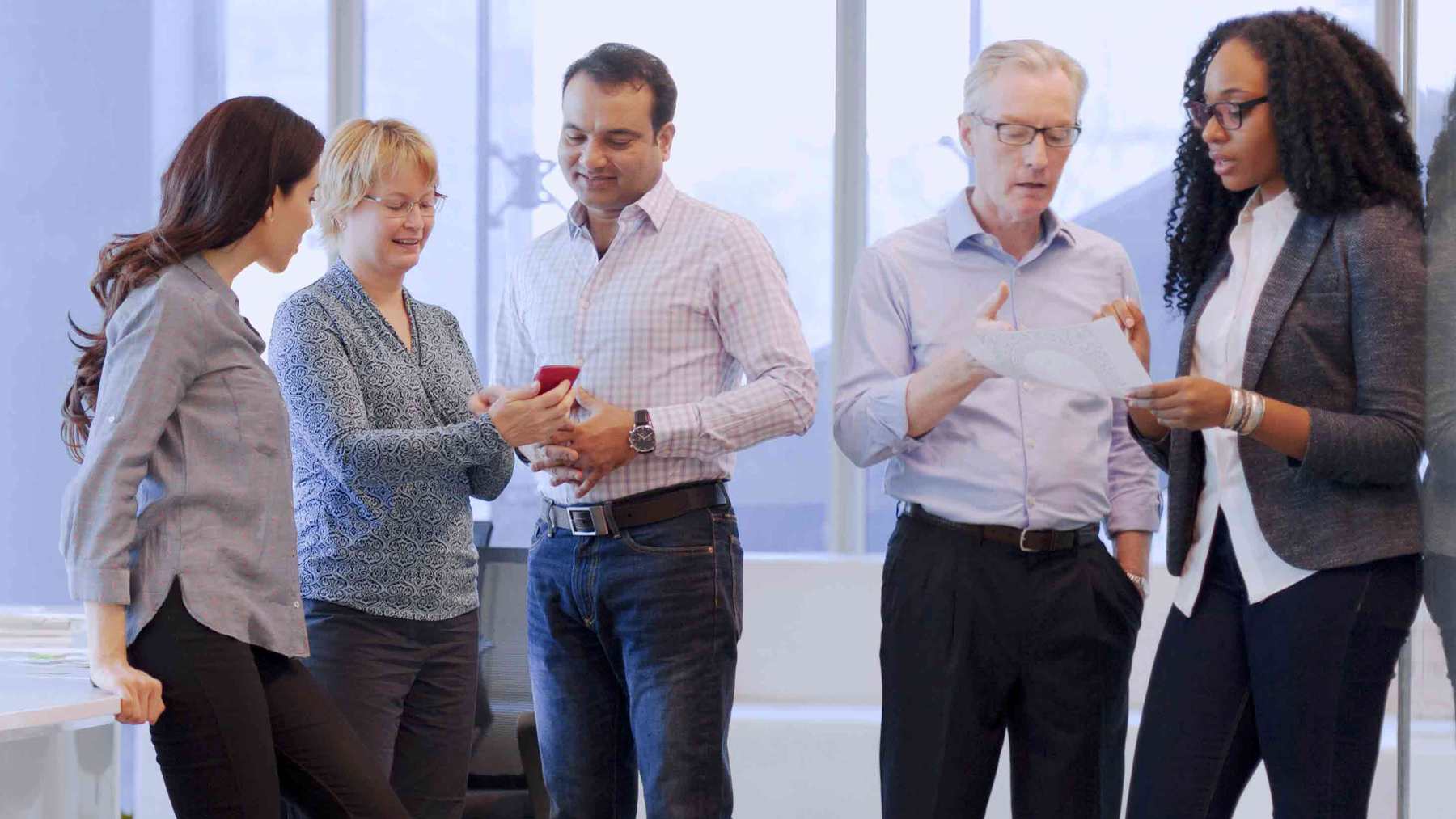 Five Viatris colleagues standing together and smiling as they talk in a bright office